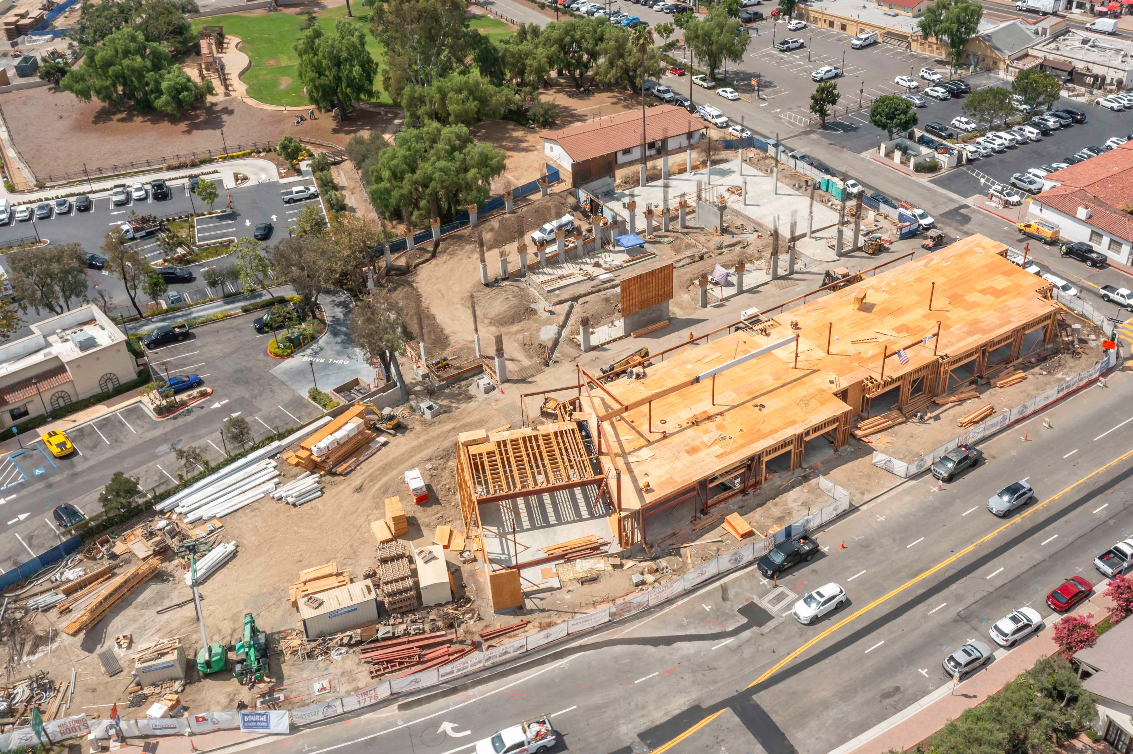 Street-facing wood framing and deck at Mission Place with concrete slab areas and upright columns behind the structure.