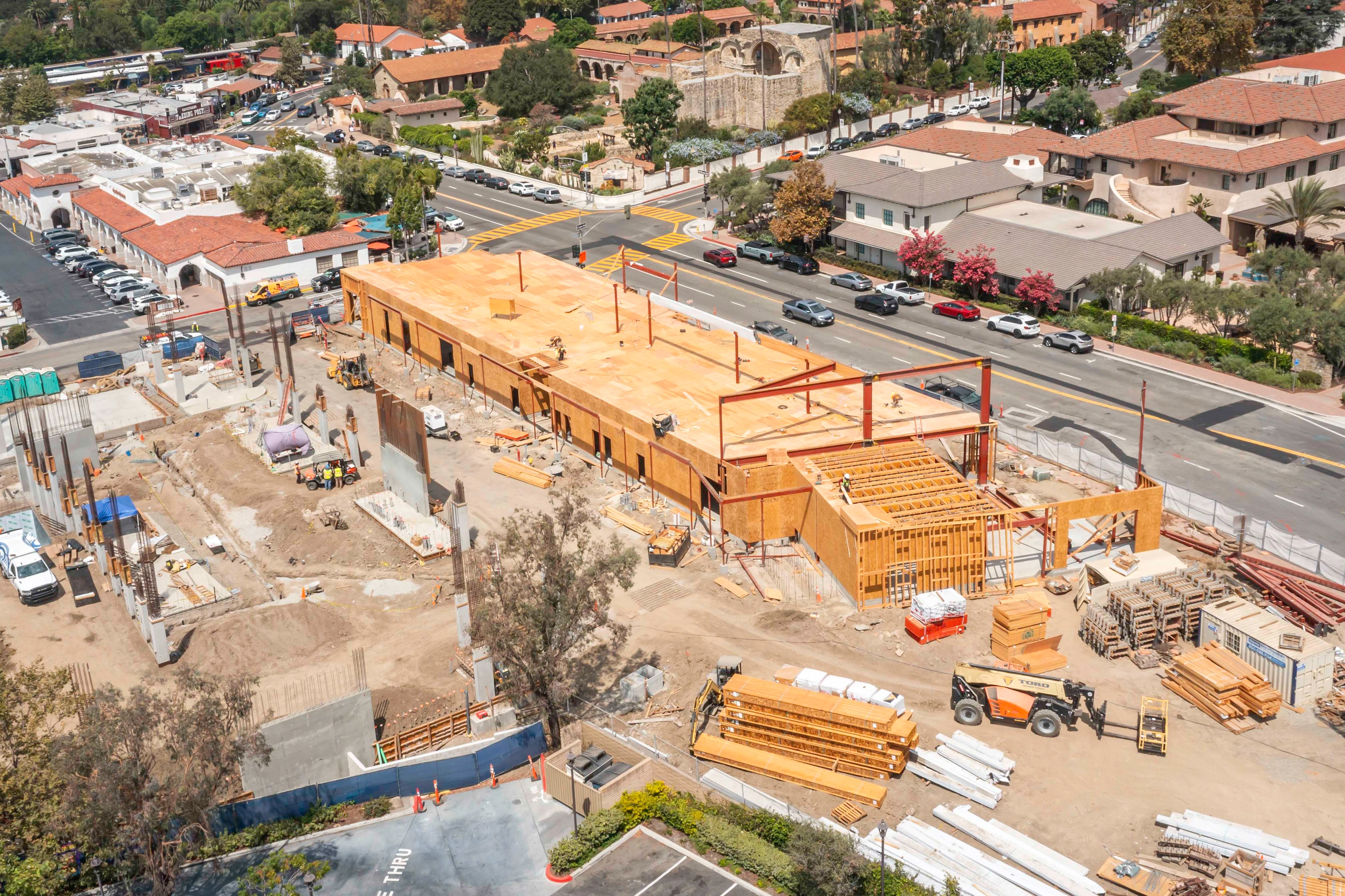 Closer elevated view of Mission Place showing wood roof decking, red steel members, exposed framing and concrete work.