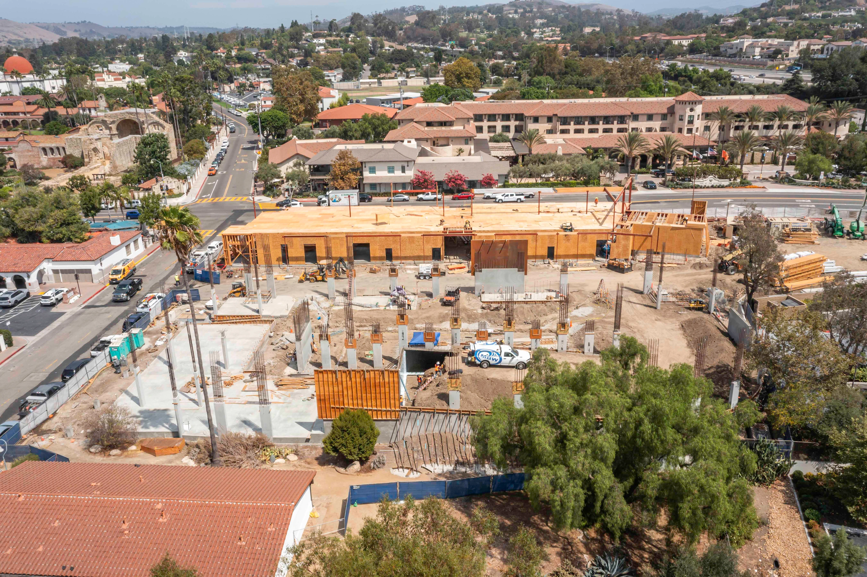 Elevated overview of Mission Place with concrete slabs, reinforcing-steel cages, wood-sheathed walls, diagonal braces and perimeter screening.